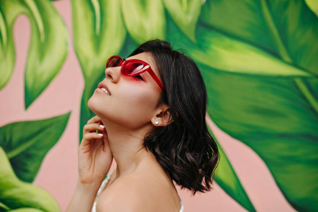 Adorable young woman with tattoo posing in front of graffiti. Outdoor shot of winsome brunette girl